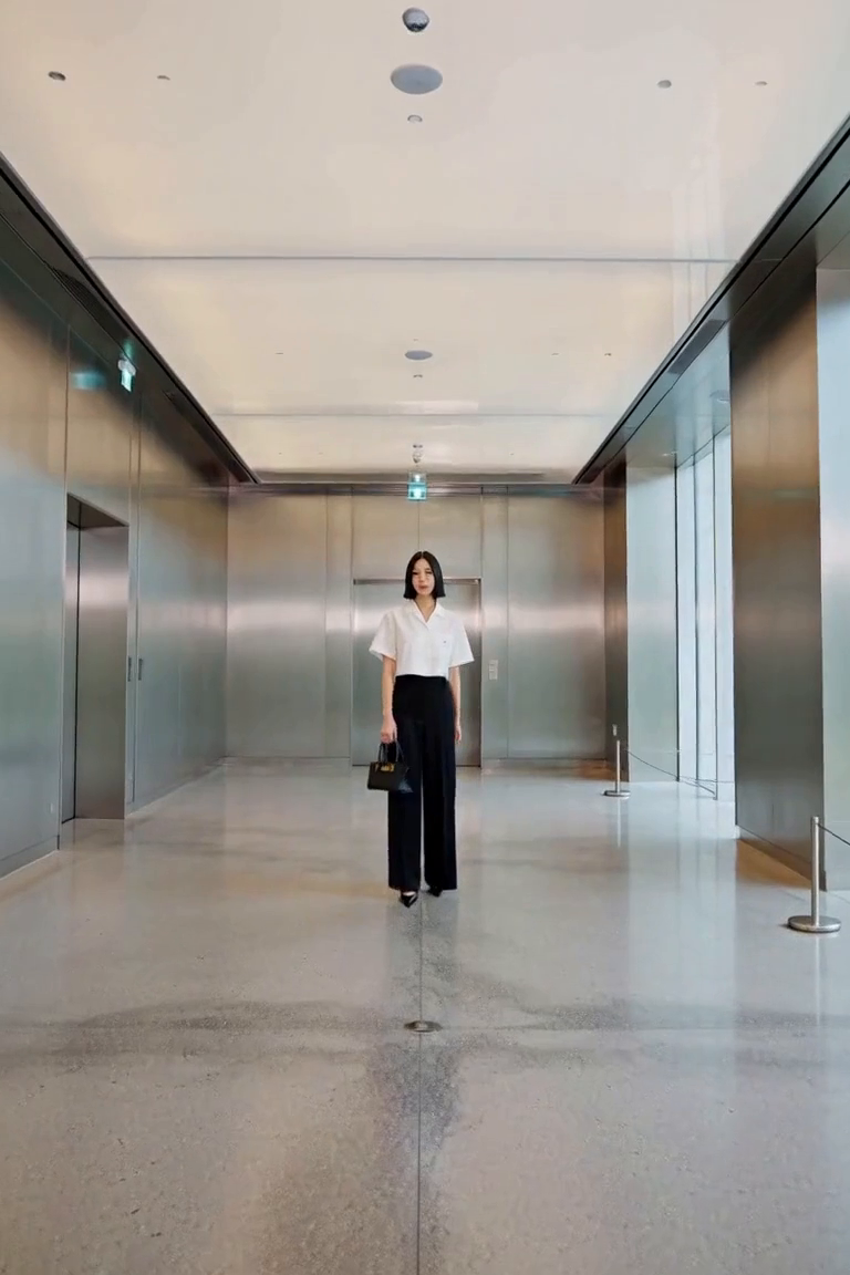 A spacious modern interior with brushed-steel wall panels and smooth grey stone floor, soft ceiling light and side daylight. No doorway framing. AI outfit styling illustration.